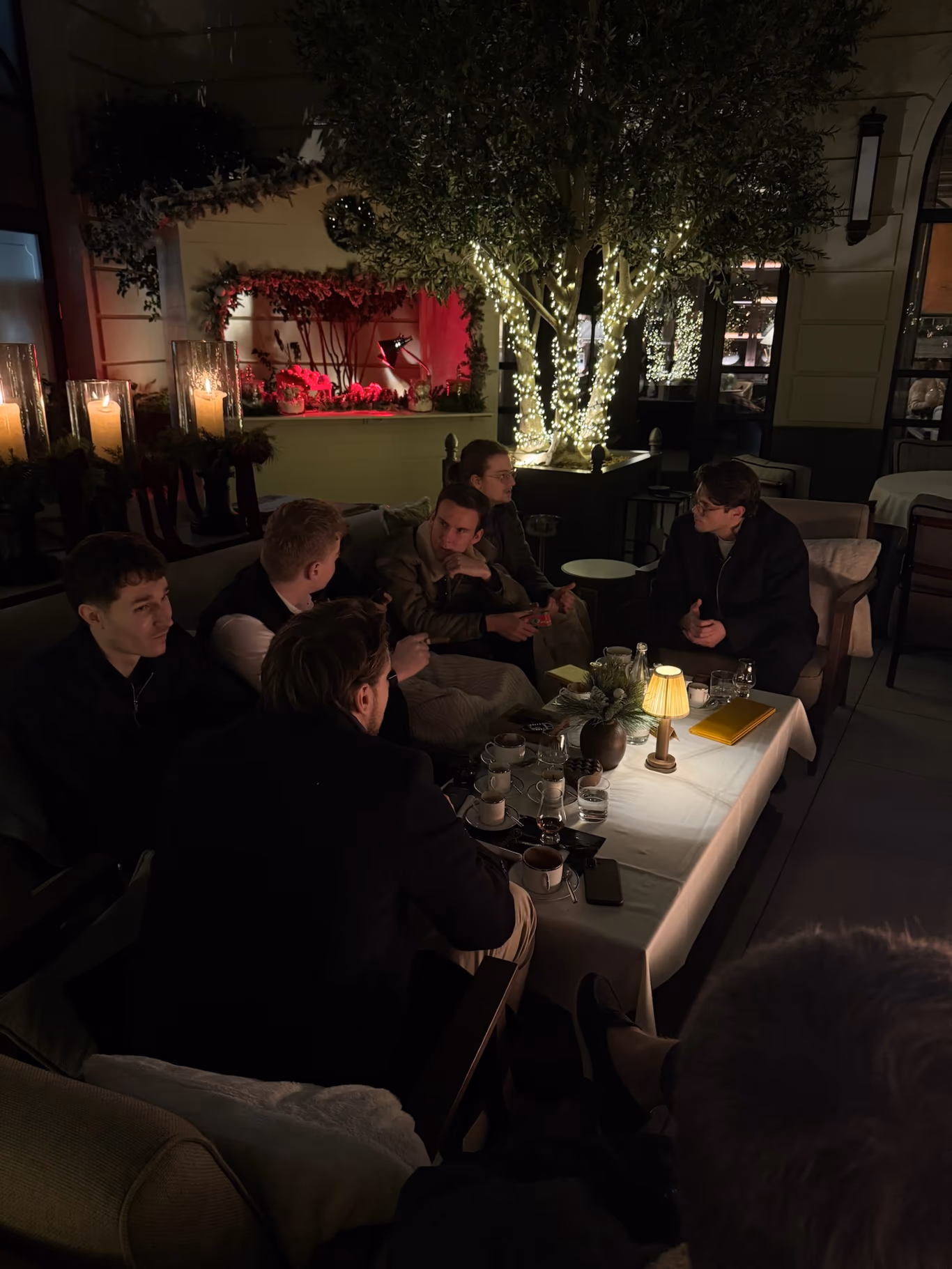 Founders leaning in over late-night coffee by candlelight — friendships built in the hours after the agenda