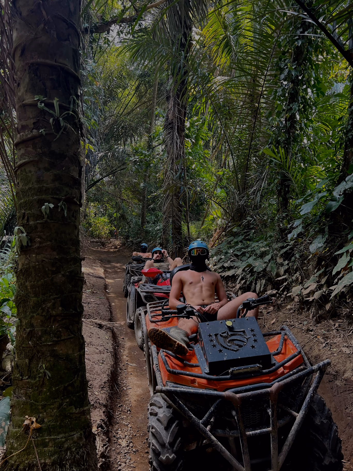 Founders riding ATVs single-file up a muddy trail through dense green jungle on a Helix retreat