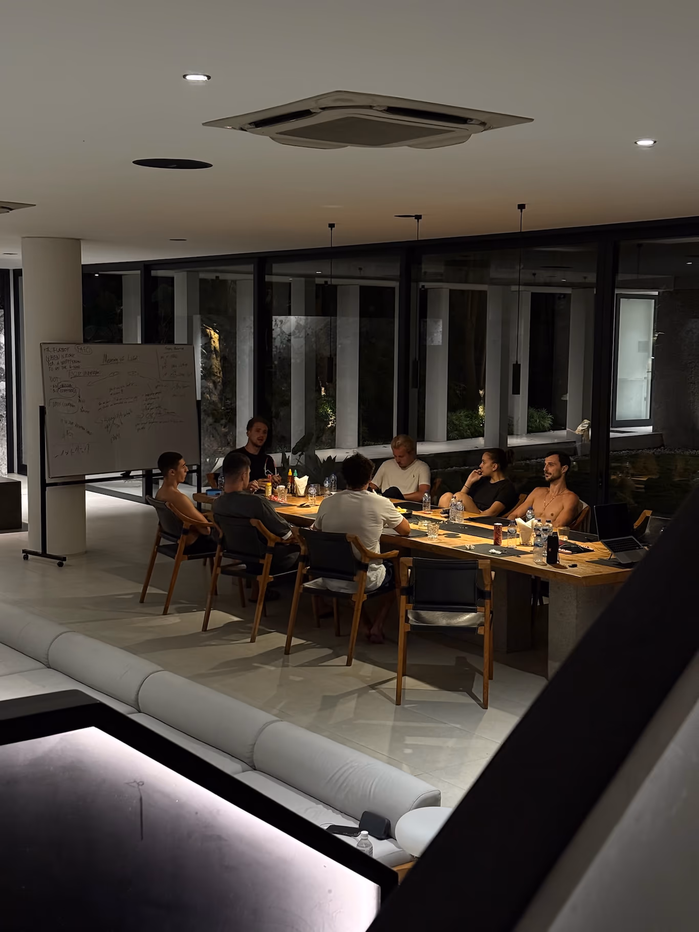 A full but private founder working session around a long table in a modern dim room