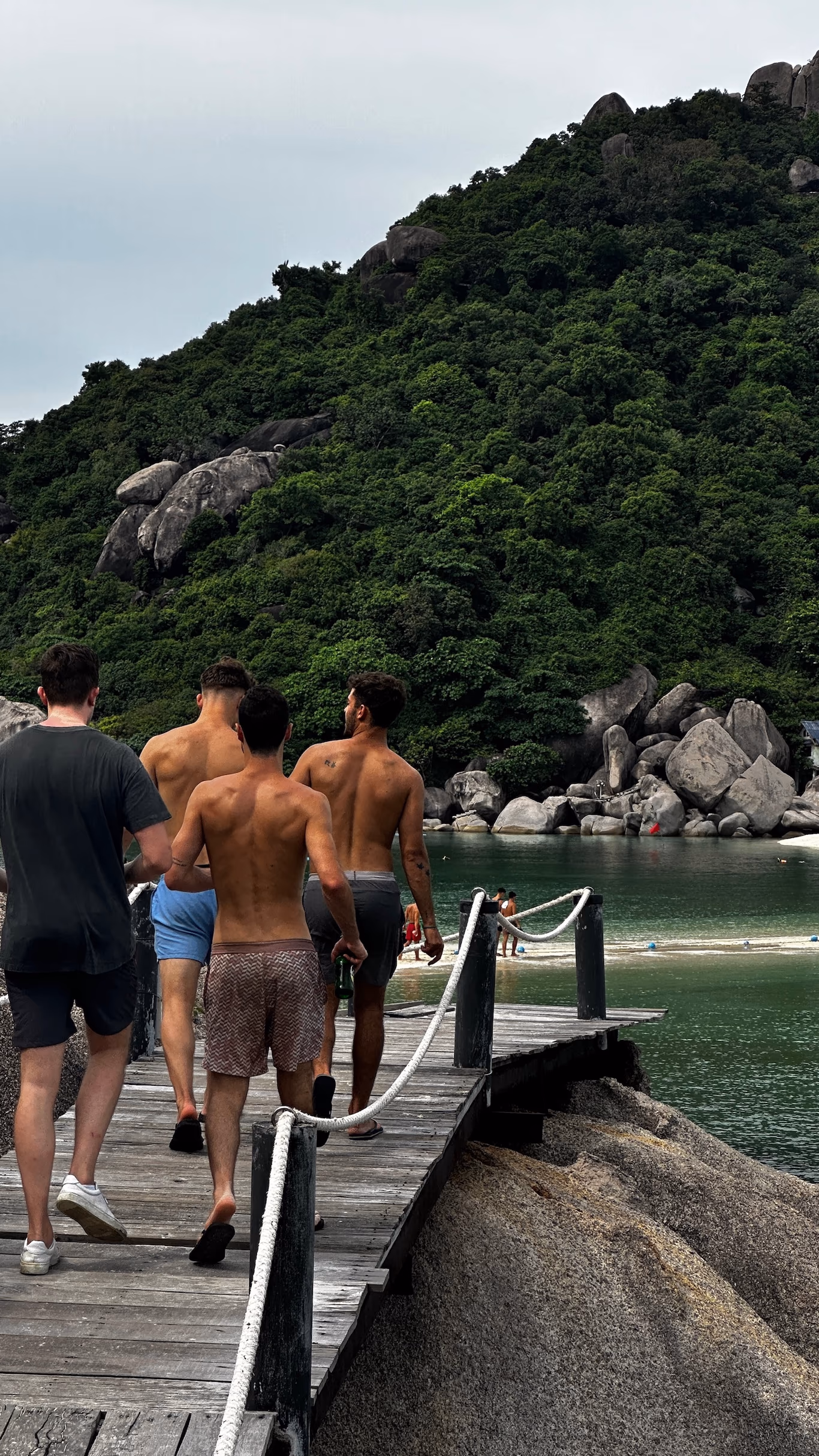 Founder travel group — walking to the water Four founders walking down a wooden dock toward the bay on a Helix trip, forested hillside behind